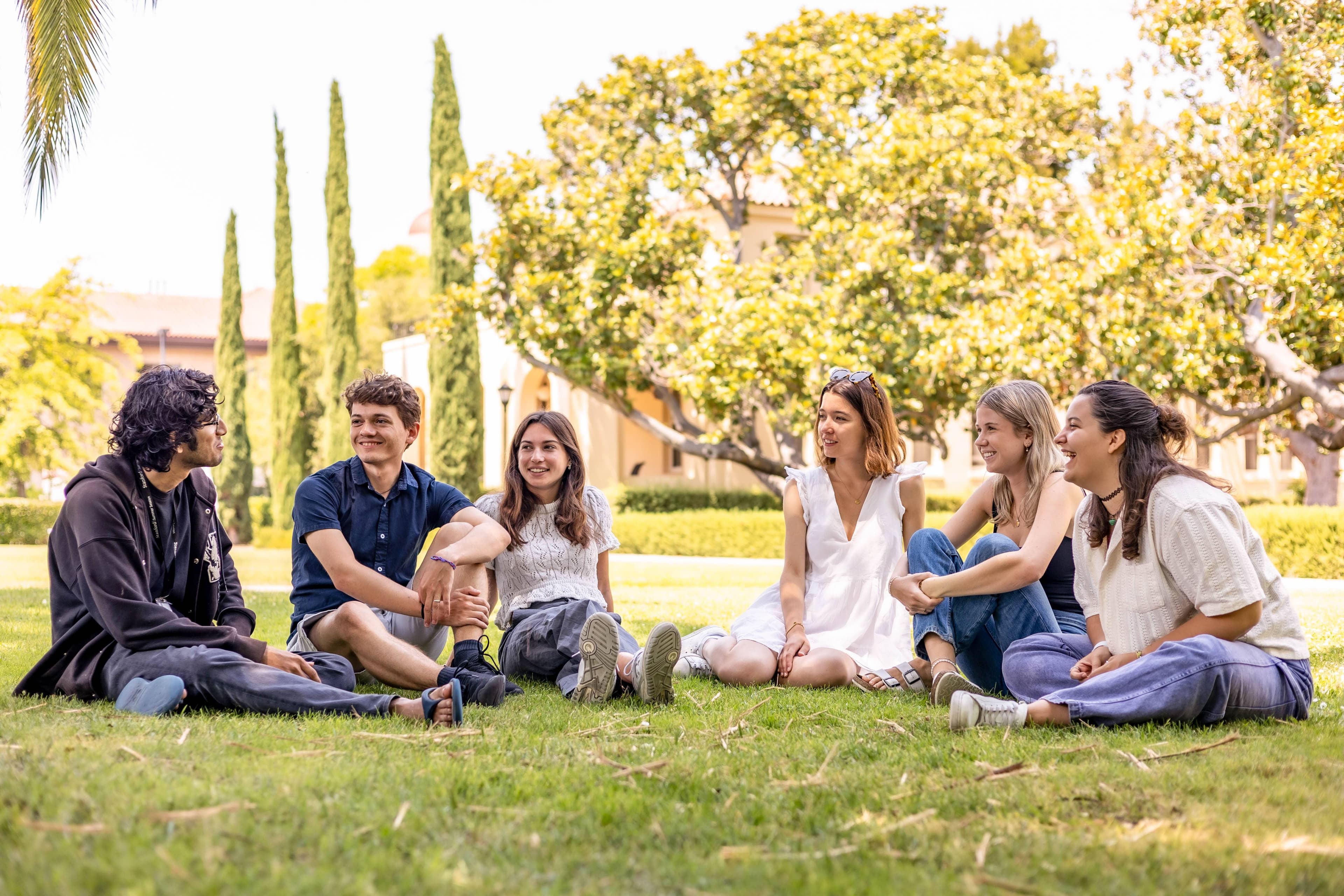 Students seated outside on a lawn.