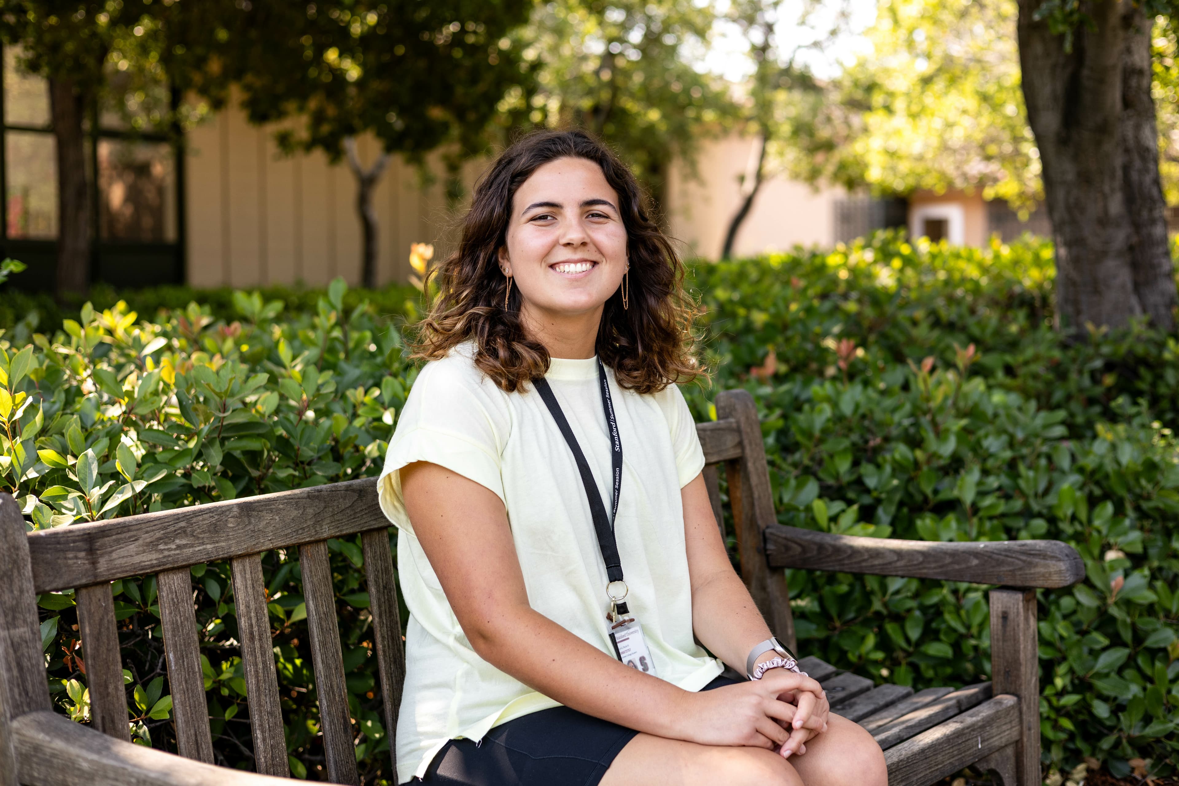 Skylar wears a white top and sits on a bench outside.