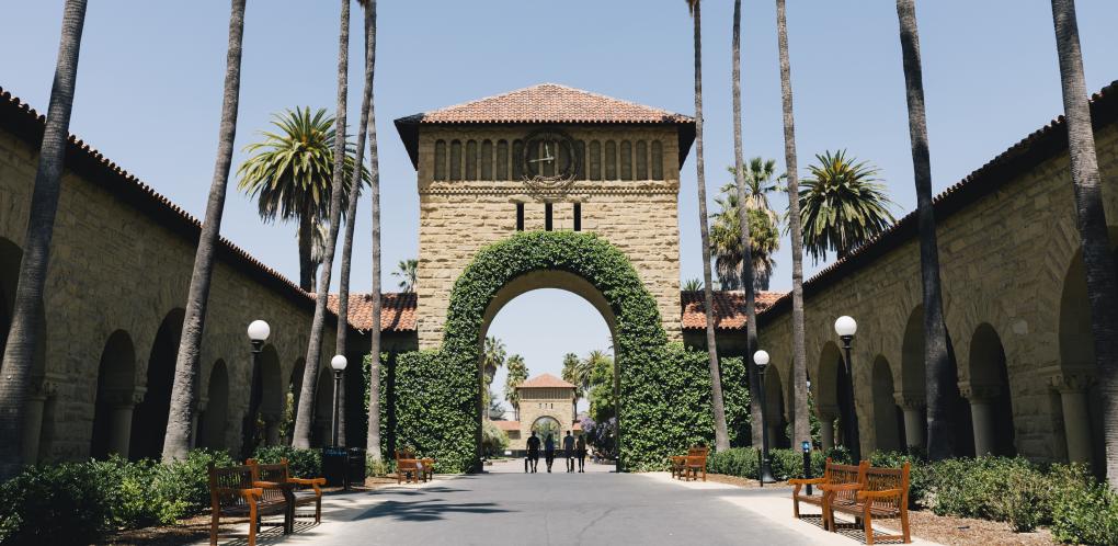 A photo of Stanford campus with a decorative arch and palm trees.